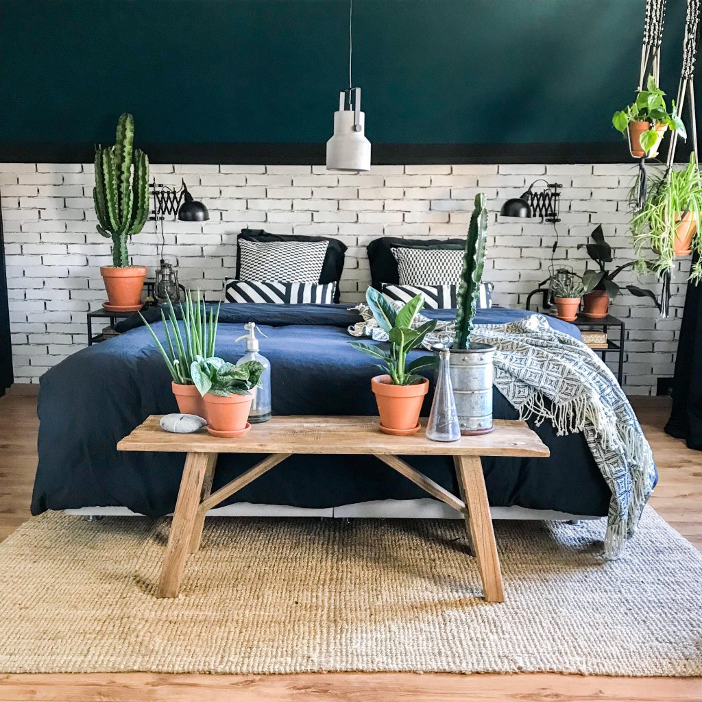 Een stoere slaapkamer vol met planten. Het Brickwall behang maakt het helemaal af.